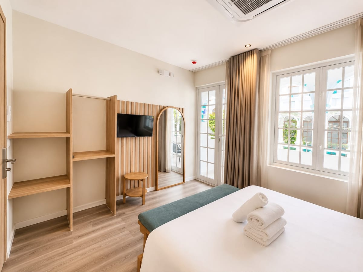 Open oak shelving and the slatted television wall, with the balcony doors and a tall street window letting in the light