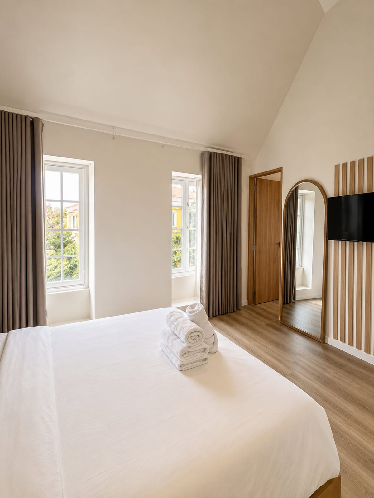 The loft with its high white ceiling, two casement windows onto Willemstad, a full height arched mirror and the slatted television wall