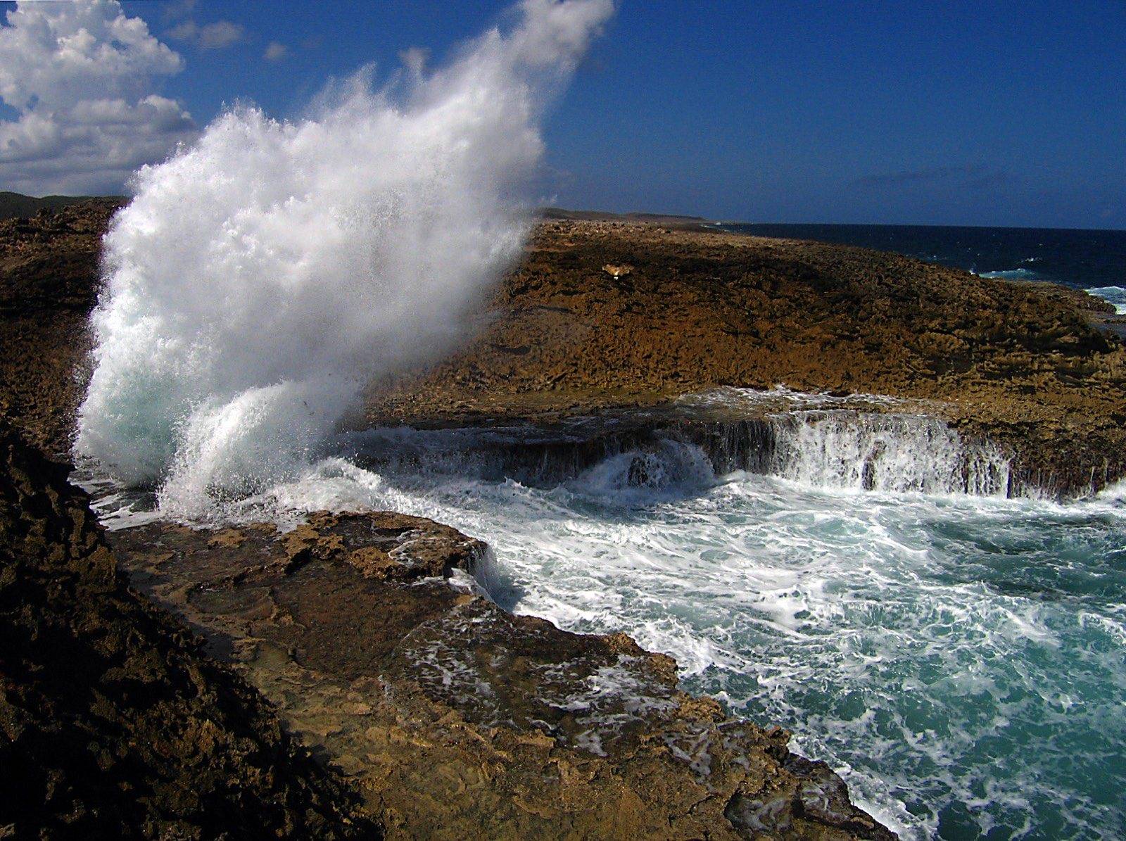 A wave exploding into white spray at Boka Pistol on Curaçao's rugged north coast