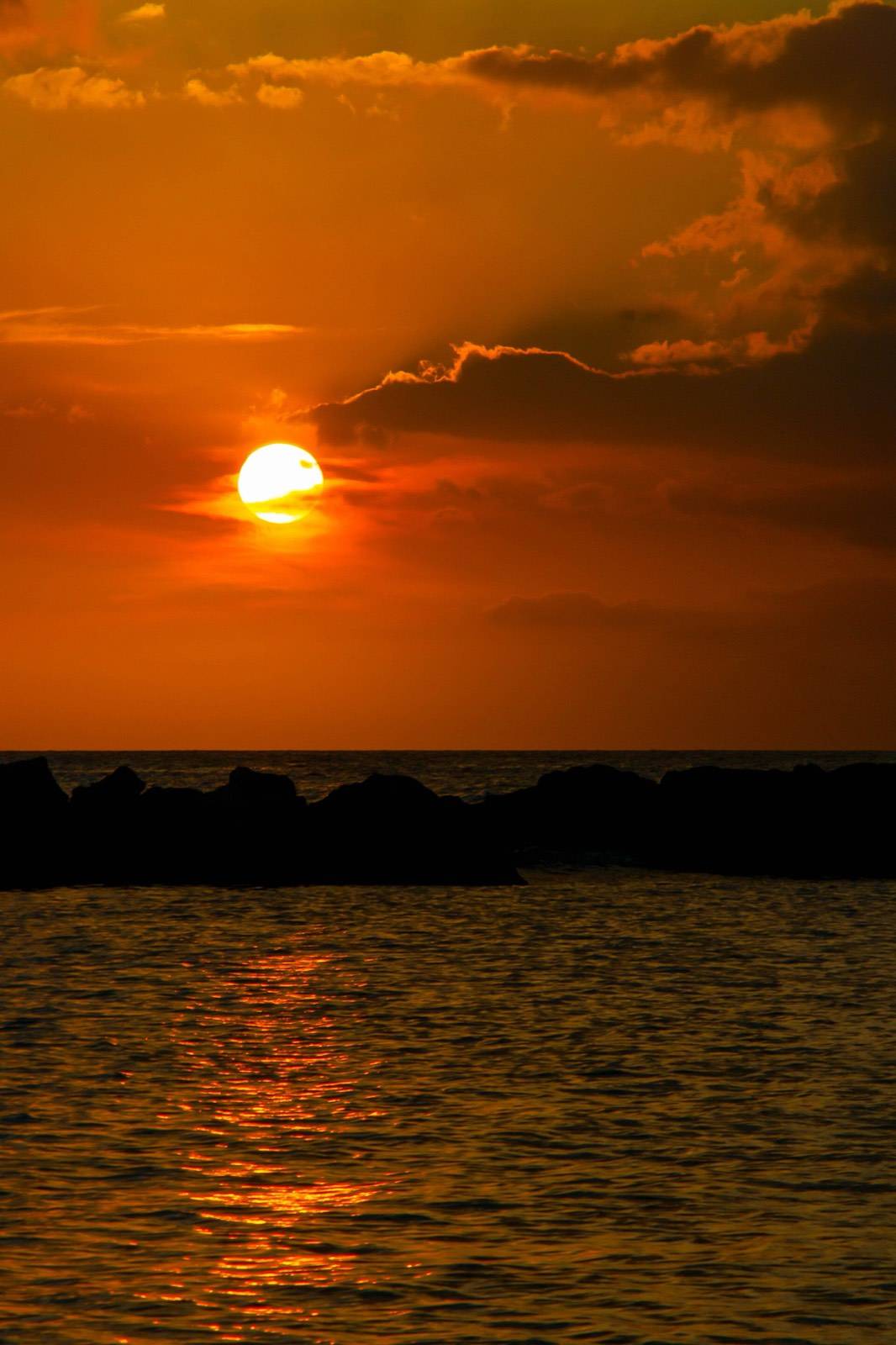 The sun setting in orange and gold over the Caribbean Sea off the Mambo Beach strip in Curaçao