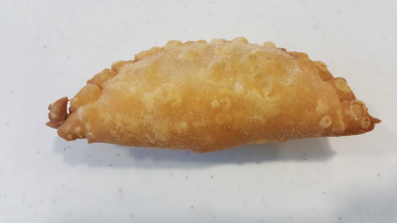 Golden fried pastechi pastries, the classic Curaçao breakfast, stacked at a snack window